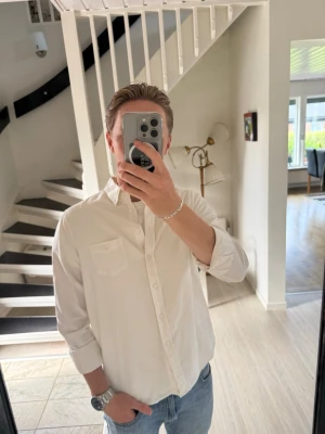 Vit skjorta i bomull från gant - Klassisk vit skjorta i bomull från gant med lång ärm och knappar framtill. Skjortan har en bröstficka och normal passform, perfekt till jeans eller chinos. Enkel och stilren design som funkar till många olika looks.
