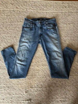 Replay anbass 32/34 - Snygga blåa jeans från Replay med klassisk femficksdesign och slitna detaljer framtill och baktill. Jeansen har normal midja, dragkedjegylf och kontrastsömmar. Perfekta för en avslappnad och trendig look. Storlek: W32 L34