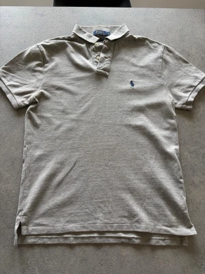 Ralph Lauren piké - En klassisk snygg grå piké från Polo Ralph Laurent. Storlek S ,slim fit. Inga defekter alls, använda några gånger. Skick 9/10. Pris kan diskuteras vid snabb affär!