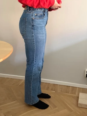 Blå raka jeans VMTessa - Klassiska blå jeans från vero moda med rak passform och hög midja. Jeansen har fem fickor, knappgylf och är tillverkade i ett slitstarkt denimtyg. Perfekta för en avslappnad och tidlös stil.
