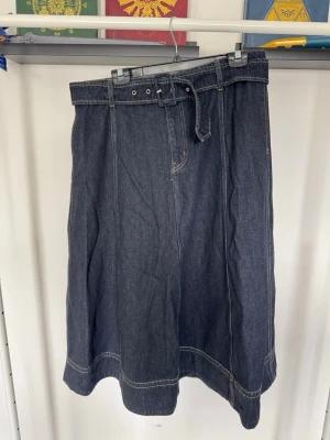 Mörkblå jeanskjol med bälte - Snygg mörkblå jeanskjol i klassisk modell med tillhörande bälte i midjan. 