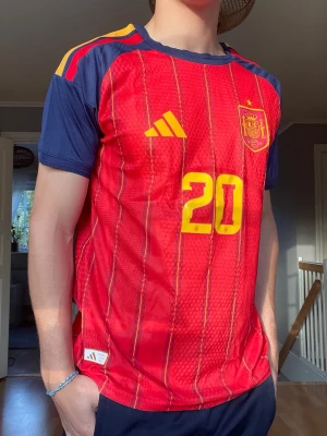 Spanien Matchtröja – Pedri #20 – Adidas – Mycket fint skick - Säljer en snygg Spanien-tröja med Pedri #20 på ryggen. Tröjan har den klassiska röda designen med marinblå detaljer och Spaniens landslagsmärke på bröstet. Perfekt för fotbollsfans, samlare eller dig som vill bära en stilren matchtröja.  • Spanien landslagströja • Pedri #20 på rygg och framsida • Adidas-design • Ventilerande och bekvämt material • Mycket fint skick • Inga hål eller större defekter  Storlek: M (L passar som M) Pris: 449 kr