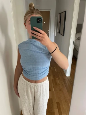 Ljusblå croppad topp med öppen rygg - Trendig ljusblå croppad topp med struktur, ärmlös design och snygg öppen rygg som knyts med band. 