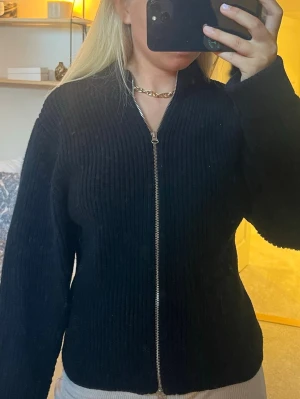 & Other stories svart zip - Säljer en svart ribbad ziptröja med hel dragkedja framtill. Super fint skick, knappt använd och väldigt fin passform längs kroppen med lite puffigare armar.