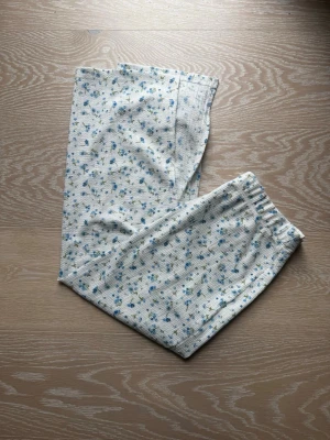 Vit blommig långkjol med resår - Supersöt långkjol i vit med små blå blommor och elastisk midja. Kjolen har en rak passform och är gjord i ett mjukt, ribbat material som känns bekvämt mot huden. Perfekt för dig som gillar en romantisk och avslappnad stil. Knappt använd
