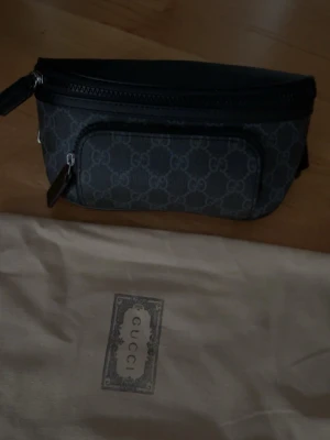 Svart Gucci Magväska - Säljer en svart axel/midje/magväska från Gucci med monogram. Man kan justera hur den ska sitta. riktigt snygg och kommer med vanlig dustbag