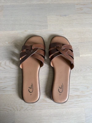 Sandaler  - Fina bruna sandaler med flätade remmar. Använda endast en gång. Nypris 299 kr