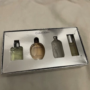 Calvin Klein parfymset 4-pack - Nytt/ickeöppnat set  från Calvin Klein med fyra olika miniflaskor: Eternity i ljusgrön glasflaska, Obsession i rund beige flaska, CK One i matt silverfärgad flaska och Escape i smal cylinderformad flaska. Alla flaskor ligger i en snygg silverfärgad presentask.