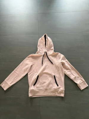 Ljusrosa Hollister hoodie med svarta detaljer - Snygg ljusrosa hoodie med huva och svarta dragsnören. Den är i väldigt bra skick:)
