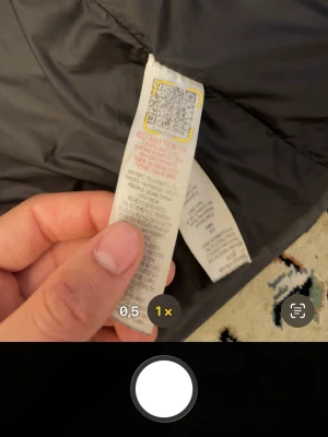 Svart dunjacka med huva - Snygg svart dunjacka med huva och dragkedja framtill. Jackan har två fickor med dragkedja och en längre modell som håller dig varm under kalla dagar. Perfekt för vintern och har en stilren look som passar till det mesta.