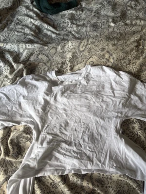 Vit croppad t-shirt i bomull - En basic vit croppad t-shirt från H&M i mjuk bomull. Klassisk rund halsringning och korta ärmar. Perfekt att styla till jeans eller kjol för en enkel och clean look. går att knyta till rosett i ryggen