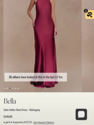 Vinröd satin maxiklänning Bella - Elegant vinröd maxiklänning i satin med halterneck och öppen rygg. Klänningen har en lång, figurnära siluett som faller snyggt mot kroppen och ger en lyxig känsla. 