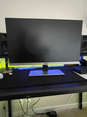 AOC datorskärm svart/silver - Snygg AOC datorskärm med tunn ram i svart och silver. Skärmen har en stilren, rektangulär fot i metall och anslutningar på baksidan för HDMI och VGA. Perfekt för gaming, studier eller jobb vid skrivbordet.