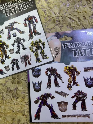 Transformers temporära tatueringar - Säljer ark med temporära tatueringar med Transformers-motiv. Flera olika robotar i färger som gul, svart, röd och lila samt logotyper från serien. Perfekt för dig som vill ha coola och färgglada motiv på huden ett tag. Lätta att applicera och ta bort. 50kr/2st/ :bild 