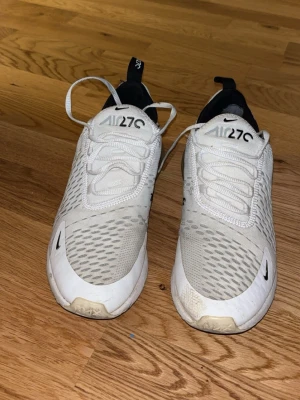 Nike Air Max 270 vita sneakers st 40.5 - Nike Air Max 270 sneakers i vitt med svarta detaljer och stor synlig luftkudde i hälen. Ovandelen är i mesh och syntet, med snörning och rund tå. Snyggt sportig design med logga på plösen och sidan. Perfekt för dig som gillar streetstyle och komfort. Broshans skor då han slutat använda de , dom e väl omhändertagna och är i rätt så bra skick så sista pris 450(passar storlek 41 med) dom. E k bra skick men kan få dom muclet renare 
