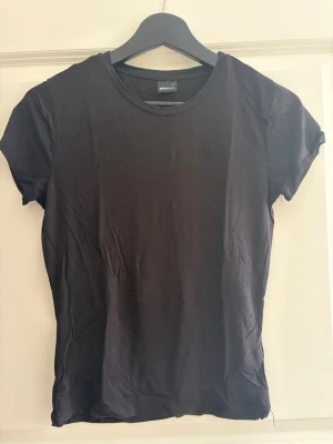 Svart basic t-shirt från Gina Tricot - En enkel svart t-shirt från Gina Tricot med rund halsringning och korta ärmar. Tillverkad i mjuk bomull som känns skön mot huden. 