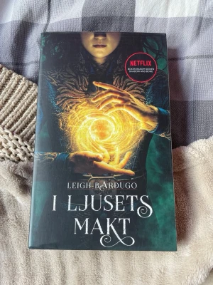 I ljusets makt av Leigh Bardugo - Säljer boken 'I ljusets makt' av Leigh Bardugo, första delen i Grisha-trilogin. Omslaget är mörkt med ett magiskt ljusmotiv och text i vitt. Boken är på svenska och har koppling till Netflix-serien Shadow and Bone. Perfekt för dig som gillar fantasy och äventyr.