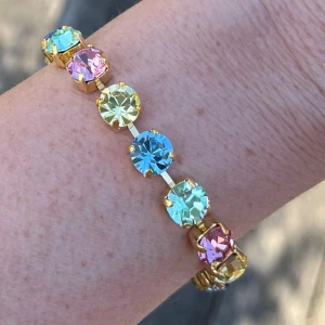 Armband med kristaller Rainbow  - Armband med blandade kristaller, egen design. Guldpläterad mässing.  Pastellfärger, light Sapphire, Chrysolite, Light Rose och Jonquill, 15st ss39 8mm stora kristaller. Längd 23,5cm inkl lås och förlängningskedja. Finns även i andra färger på kristallerna.  Jag skickar endast spårbart, samfraktar. Fast pris. Besök gärna mina övriga annonser.  Till mina smycken använder jag kristaller från Preciosa, Aurora och Swarovski.