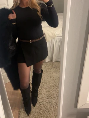 Svart långärmad body i bomull - Snygg svart långärmad body med rund halsringning. Toppen är figurnära och enkel i modellen, perfekt att styla med kjol eller jeans. Tillverkad i mjuk bomull som känns skön mot huden. Passar dig som gillar en clean och stilren look.