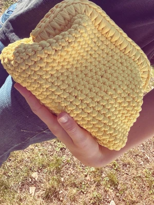 Gul clutchbag  - Unik handgjord clutchbag i solgul färg, virkad i tjockt garn för en cool och trendig look. Väskan har en mjuk och flexibel form, perfekt för att bära det viktigaste. Ingen synlig logga eller märke. Passar dig som vill sticka ut med accessoarer. Följ oss gärna på tiktok och insta: viraclutch💞💞