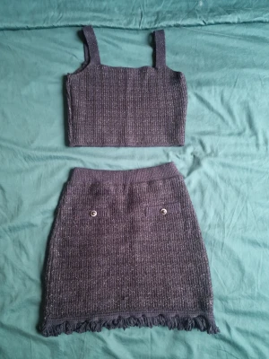 Marinblått set från Mango  - Stickat set med topp och kjol som har fransar längst ner och två dekorativa knappar framtill. Toppen har storlek L men passar mig som har S (liten storlek) kjolen är i storlek S. 