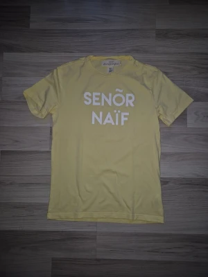 Gul  topp från H&M  - Gul topp från H&M med vit text på bröstet. Klassisk rund halsringning och korta ärmar. Tillverkad i mjuk bomull som känns skön mot huden. Perfekt för dig som gillar färg och vill sticka ut lite extra.