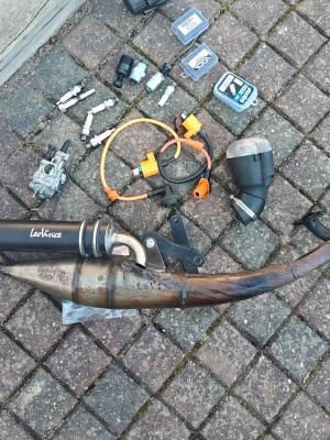 Mopeddelar och avgassystem LeoVince - Säljer ett paket med mopeddelar inklusive ett avgassystem från LeoVince, tändspolar med orange kablar, tändstift, förgasare, blinkers och diverse smådelar. Perfekt för dig som vill meka med moppe eller behöver reservdelar.