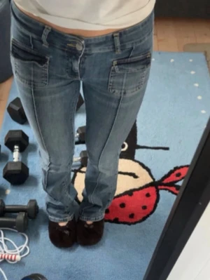 Blå jeans med kontrastfickor - Säljer ett par blå jeans med raka ben och mörka kontrastfickor framtill. Jeansen har synliga sömmar och klassisk femficksdesign. Perfekta för en avslappnad och trendig look.