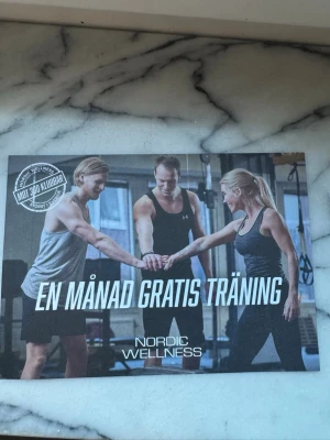 Träningskort Nordic Wellness - Kort för en månad gratis träning på Nordic Wellness. Kortet är i pappersformat och har tryckt text och bild på framsidan med tre personer i träningskläder. Perfekt för dig som vill testa gym eller gruppträning.