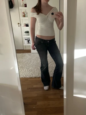 Vit omlottopp med twistad detalj - Säljer en vit omlottopp med twistad detalj framtill. Toppen är axelbandslös och har en snygg v-ringad skärning. Materialet känns mjukt och stretchigt, troligen bomull eller polyester. Perfekt till jeans eller kjol för en trendig look. Står storlek M men den är väldigt stretchig och upplevs som mindre.