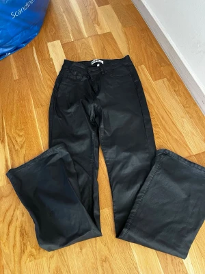 Svarta raka jeans i skinnimitation från ONLY - Snygga svarta jeans i skinnimitation från ONLY med bootcut passform och klassisk femficksdesign. Jeansen har normal midja och är tillverkade i ett mjukt, stretchigt material som ger en bekväm känsla. Perfekta för dig som gillar en clean och stilren look. Lite upprivna i slutet på bena.