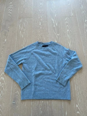 Ljusblå stickad tröja Vero Moda - Mysig ljusblå stickad tröja från Vero Moda. Tröjan har rund halsringning, långa ärmar och ribbade muddar vid ärmslut och nederkant. Perfekt för lager på lager och enkel att matcha till jeans eller kjol.