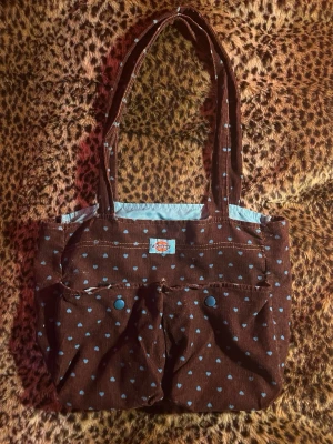 Vintage väska - Jättesöt vintage manchesterväska med blåa hjärtan på från dickies!! Man får plats med det mesta i den o passar perfekt som skolväska:)
