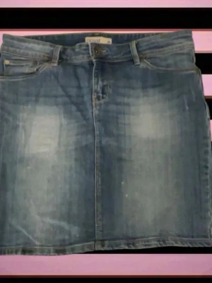 Blå jeanskjol med fickor - Säljer en klassisk blå jeanskjol i kort modell med fem fickor och bälteshällor. Kjolen har en rak passform och stängs med knapp och dragkedja framtill. Perfekt till vardags för en avslappnad look.