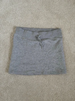 Grå kortkjol - En jättefin grå kort kjol från Bik Bok i storlek S. Kjolen är i ett mjukt material och i väldigt bra skick då den inte kommit till användning.