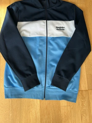 Djurgården zip hoodie blå/vit - Snygg zip hoodie från Djurgården i marinblått, ljusblått och vitt. Broderad text 'Djurgården Stockholm' på bröstet. Använd 1 gång endast 
