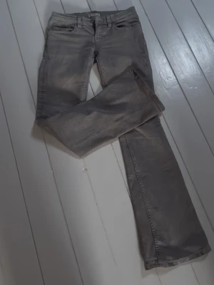 Gråa jeans från Ginatricot - Säljer ett par gråa jeans från Ginatricot  med klassisk femficksmodell och normal midja. Jeansen har raka ben och är tillverkade i ett mjukt bomullsmaterial med lite stretch för extra komfort.