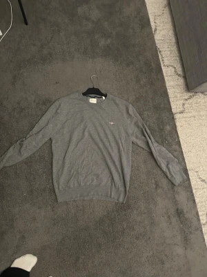 Grå sweatshirt från GANT - Sitter som S. Klassisk grå sweatshirt från GANT med rund halsringning och diskret logga på bröstet. Tröjan har lång ärm och är tillverkad i mjuk bomull, perfekt för en chill och stilren look.
