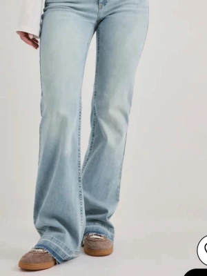 Ljusblå bootcut jeans utan midja short - Snygga ljus blåa jeans med bootcut-modell och utsvängda ben. Klassisk femficksdesign och låg midja. Jeansen har en tvättad look och är tillverkade i denim med lite stretch för skön passform. De är i short så passar dig som är runt 160💕