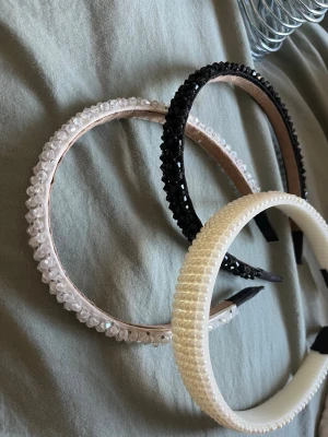 3-pack diadem med pärlor och stenar - Säljer ett set med tre diadem: ett vitt med små pärlor, ett svart med glittrande stenar och ett transparent med kristalliknande dekorationer. Alla har en klassisk rundad form och är perfekta för att lyfta vilken outfit som helst.