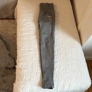 Grå träningstights med scrunch från Peach - Grå tights från Peach med hög midja. Tillverkade i stretchigt material som sitter tight och bekvämt. Perfekta för gym, yoga eller löpning. Endast använda en gång.