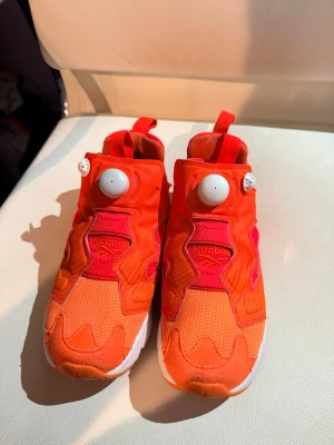 Reebok Instapump Fury orange sneakers - Säljer ett par Reebok Instapump Fury sneakers i en riktigt fet orange färg med röda detaljer. Skorna har den ikoniska pumpfunktionen och en chunky vit sula. Ovandelen är i mesh och syntetmaterial för maxad komfort och stil.