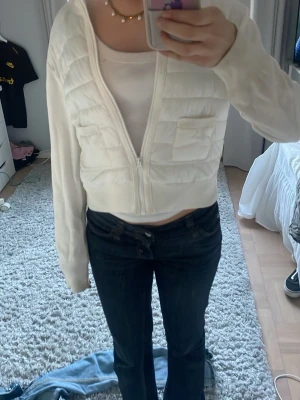Vit croppad pufferjacka med dragkedja - Säljer en vit croppad pufferjacka med quiltad framsida och två fickor. Jackan har långärmade ribbade ärmar och dragkedja framtill. Perfekt för dig som gillar en clean och fräsch stil med lite edge. Liten i storlek så skulle säga att den passar 158-164 också. Pris kan diskuteras 💕kan ha några smink fläckar men kommer tvätta jackan innan någon köper🤗