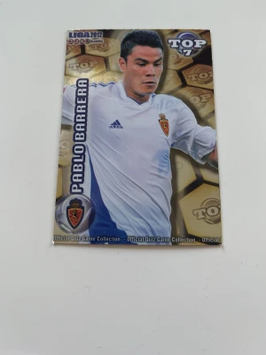 Pablo Barrera fotbollskort - Samlarbild från Liga 2012 med fotbollsspelare i vit Real Zaragoza-tröja. Kortet har guldiga detaljer och quizfråga på baksidan. Perfekt för dig som gillar fotboll, samlarkort och sportquiz. Pris kan diskutwras