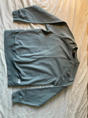 Grön-grå  sweatshirt från Lager 157 - En stilren grå sweatshirt från Weekday med rund halsringning och ribbade muddar vid ärmslut och nederkant. Tröjan har en avslappnad passform och är tillverkad i mjukt bomullsmaterial. Perfekt för en casual look.