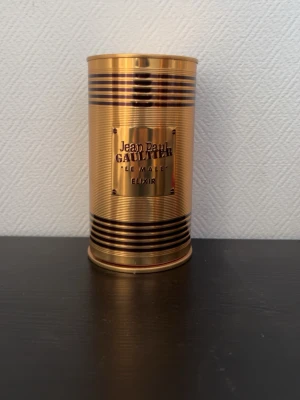 Jean Paul Gaultier Le Male Elixir - Jean Paul Gaultier Le Male Elixir parfym i en lyxig guldfärgad metallflaska formad som en manlig torso. Flaskan har eleganta ränder och kommer med en matchande guldfärgad metallburk. Perfekt för dig som gillar exklusiva och unika dofter.