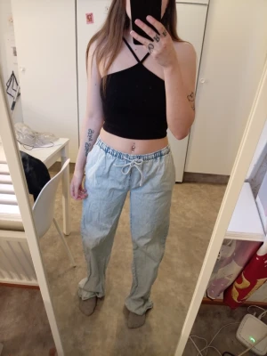 Ljusblå baggy jeans med dragsko - Säljer ett par ljusblå baggy jeans med avslappnad passform och dragsko i midjan. Jeansen har raka ben och är perfekta för en chill och trendig look. Tillverkade i klassiskt denimtyg. Perfekta för dig som gillar streetwear-vibbar.