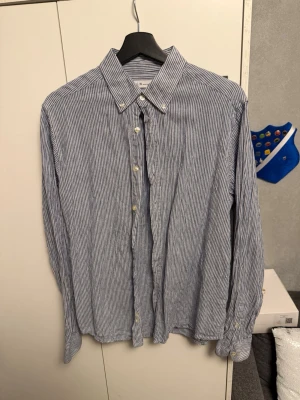 Blårandig skjorta  - Ljusblå randog skjorta. Ändast använd ett fåtal gånger och säljer den för att den inte passar mig så som jag vill ha den. Ingen skada alls, bara lite skrynklig men det löser jag innan jag skickar den! Hör gärna av er vid fler frågor! 