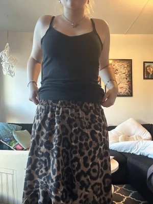 Leopardmönstrad långkjol med volang - Säljer en snygg långkjol med leopardmönster i bruna och svarta toner. Kjolen har volangdetalj nedtill och resår i midjan för skön passform. Perfekt för dig som vill sticka ut lite extra med ett djuriskt print.