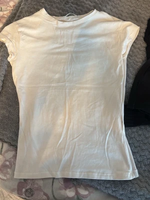 Vit basic t-shirt i bomull - Enkel vit t-shirt med korta ärmar och rund hals. Modellen är figurnära och passar perfekt till jeans eller kjol. Tillverkad i mjuk bomull för en bekväm känsla hela dagen. Aldrig använd 